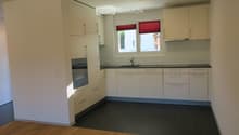 Modern kitchen with white cabinets, black countertops, and a dark tiled floor. Features a sink with a faucet and an oven built into the cabinetry.