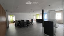 Modern office space with desks, chairs, and cabinets. Tiled floor and white walls. Office equipment and lamps visible.