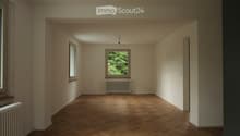 Empty room with wooden herringbone flooring, light-colored walls, and two windows with radiators beneath them.