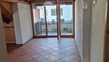 Spacious hallway with exposed wooden beams, terracotta tiled floor, and large sliding glass doors leading to a balcony.