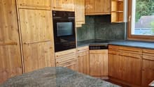 Wooden kitchen with granite countertop, built-in oven, and wooden cabinets.