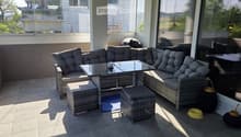 Balcony with wicker seating, glass coffee table, and outdoor view.