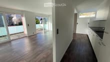 Empty room with tiled floor, white walls, and large windows leading to a balcony. The room is unfurnished and has a modern design.