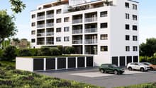 Modern multi-story residential building with balconies, garage, and parking area.