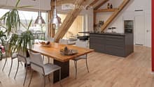 Open-plan kitchen and dining area with light wooden flooring, exposed wooden beams, modern kitchen island with cabinets, dining table with chairs, pendant lights, and decorative bowl on the table.