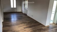 empty room with white walls, wooden floors, two windows, radiator