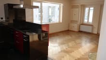 Black and red cabinets, stainless steel appliances, black granite countertops, herringbone wood floors, large window, radiator
