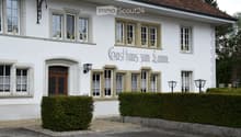 White building with multiple windows, decorative stone trim, and a sign reading "Gasthaus zum Lamm".