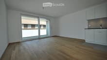 Empty room with wooden flooring, white walls, and a sliding glass door leading to an outdoor area. Minimalist design with built-in cabinets and a countertop on the right side.
