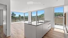 Modern kitchen with light-colored cabinets, a central island, and large windows offering a scenic view of the landscape.