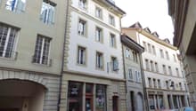 Multi-story building with classic European architecture, large windows, and a storefront at the ground level.