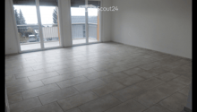 Empty room with tiled floor and large sliding glass doors leading to a balcony area.