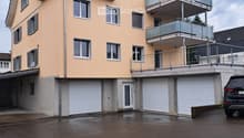 Two-story house with beige exterior, multiple windows, garage, and balcony on the upper level.