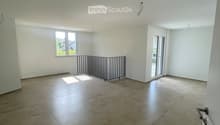 Empty room with tiled floor, white walls, and large windows, featuring a metal safety barrier near the window.
