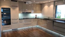 modern kitchen, stainless steel appliances, LED lighting, wooden floors, white cabinets, marble countertop