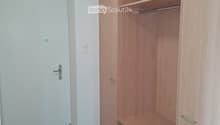 Empty room with wooden floor, white walls, and built-in wooden closet with shelves and hanging rod.