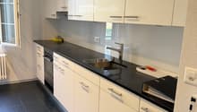 modern kitchen, black counter, white cabinets, stainless steel sink, dishwasher, washing machine, window, radiator