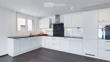 Modern kitchen with white cabinets, dark countertops, and stainless steel appliances. Features a sink, faucet, oven, and range hood.