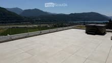 Roof terrace with tiled flooring, metal safety railing, and scenic mountain and lake view.