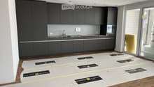 Modern kitchen with dark grey cabinets, a sink, and a wooden floor. Protective plastic sheets are laid out on the floor, likely for renovation or installation purposes.