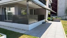 Modern two-story building with a covered balcony area, large windows, and a small garden space.