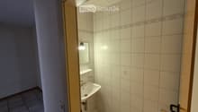 Small bathroom with white tiled walls and floor, a white sink, a mirror, and a light fixture above the sink.