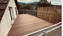 Wooden deck terrace with metal railing, bamboo screen, and scenic mountain view.