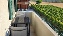 Balcony with a view of vineyards and hills, featuring a table and a chair.