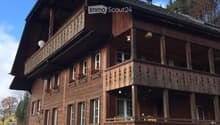 Traditional wooden house with multiple balconies, large windows, and flower boxes.
