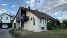 Two-story house with a modern design, featuring a balcony on the upper level, multiple windows, and a well-maintained lawn.