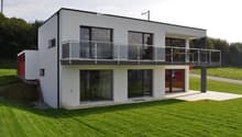 modern white house, glass windows, glass balcony, red door, large green lawn