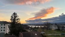 Balcony view overlooking a residential area with boats on trailers, houses, and a sunset sky.