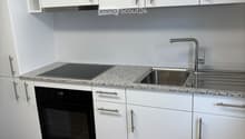 modern kitchen with white cabinetry, granite countertops, stainless steel sink and faucet, induction cooktop, built-in oven, dishwasher and washing machine visible