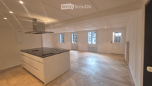 Open kitchen with island, wooden parquet floor, white walls, ceiling with recessed lighting, windows, kitchen hood, central island with sink and stove