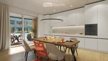 Modern kitchen with white cabinets, a wooden dining table, and a pendant light. The table is set with plates, cups, and a book, and there are chairs around it. An oven is visible in the background, and the space has large windows with a view of the outdoo