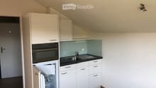 Modern kitchen with white cabinets, stainless steel appliances, and a black countertop.