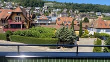 Balcony overlooking a town with houses, trees, and a clear blue sky.