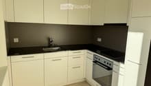 modern white kitchen with black countertops, silver sink, faucet, modern white cabinetry, oven, stove