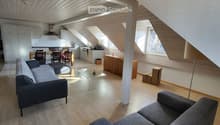2 gray couches, glass table, white cabinets, wooden table with 4 chairs, open kitchen, small window, white flooring