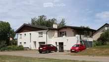 Two-story house with white siding, brown roof, garage, and two parked cars.