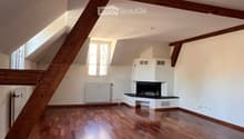 Empty room with wooden flooring, white walls, and a fireplace. Natural light from skylights and windows.