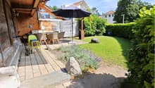 Garden with a patio area, outdoor dining set, umbrella, bicycle, and surrounding greenery.