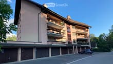 Multi-story residential building with balconies, garage, and parking area.