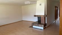 Empty room with wooden flooring, white walls, and a built-in brick fireplace.