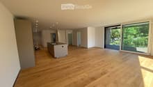 Empty room with wooden flooring, white walls, and large sliding glass doors leading to a balcony. Minimalist design with recessed lighting.