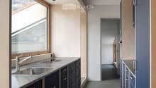 Modern kitchen with stainless steel sink, sleek faucet, and dark blue cabinets with silver handles. Large window provides natural light.