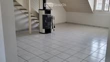 Hallway with tiled floor, staircase, and wood-burning stove with tools nearby.