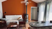 Orange walls, a white sofa with decorative pillows, a round wooden coffee table, a wooden chair, a fireplace, and a black lamp.