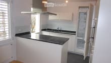 modern kitchen with island, granite countertops, stainless steel appliances, white cabinets, open refrigerator, sink with faucet, exhaust hood, wooden floor