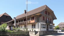 Two-story building with a restaurant sign "Restaurant Rossi" on the balcony, red shutters, and a wooden fence in front.